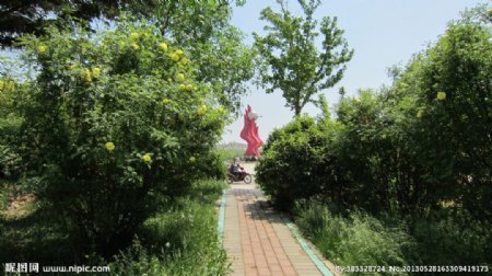 小路绿树和红色雕塑图片