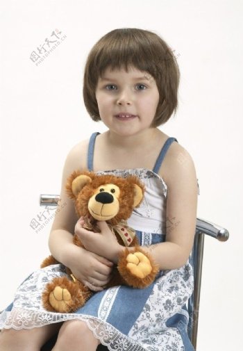 坐在椅子上抱着布娃娃的快乐孩子图片