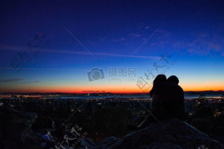 日出夫妇在灰色坐在巨石剪影照片