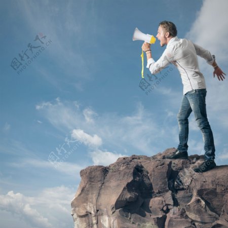 站在悬崖上大喊嗽叭的男人图片
