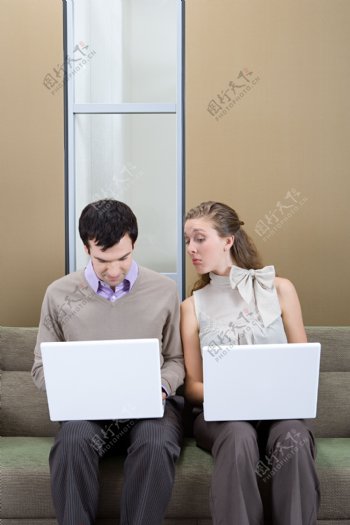 坐在沙发上玩电脑的男女图片