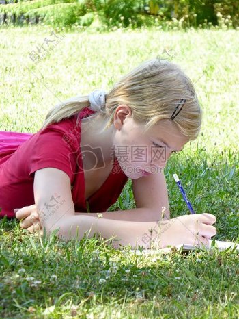 在草地上写作业的女孩