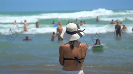 站在沙滩上戴着帽子的女人