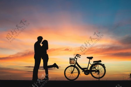 情侣与自行车在夕阳下的剪影