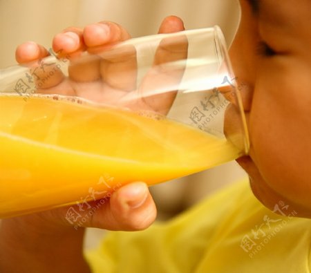 一个健康的男孩喝橙汁玻璃