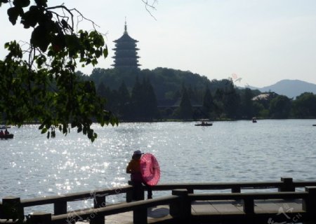 杭州西湖边撑绸伞的女孩剪影图片