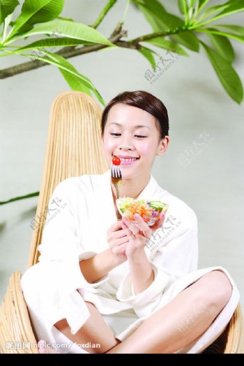 漂亮美女座藤椅微笑吃水果沙拉图片