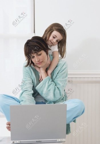 抱着妈妈脖子一起看笔记本电脑的母女图片