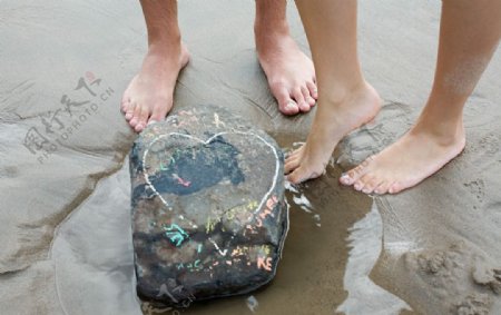光脚的沙滩恋人石块上的爱心图片