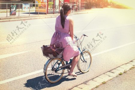女性在紫色长裙骑在自行车城市道路