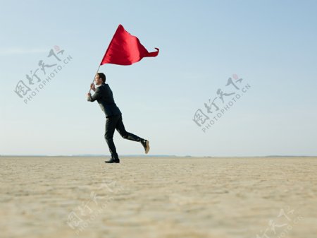烈日下扛着红旗在奔跑的外国男士图片