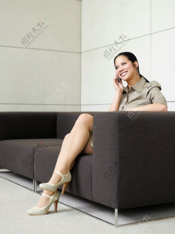 坐在沙发上接电话的女性图片