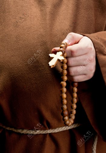 手拿珠链十字架祈祷的男人图片