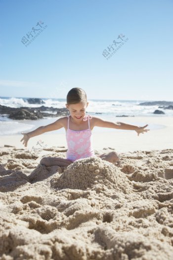 沙滩上玩沙子的女孩图片