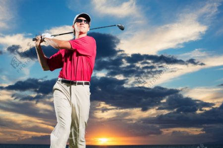 夕阳下挥动高尔夫球杆的男人图片