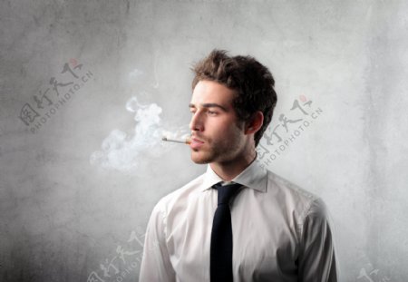 站在墙壁前吸烟的外国男人图片