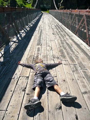 疲倦的男孩躺在木桥上
