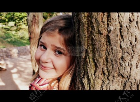 站在树干旁边的小女孩