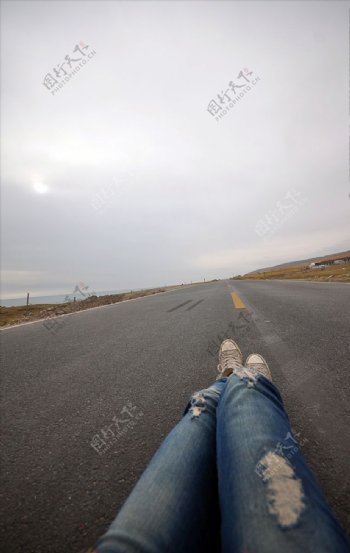 牛仔裤长腿躺在公路上